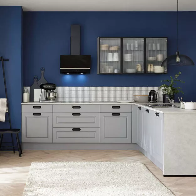 Landhausküche in Blau und Grau mit Kassettenfronten und Glasoberschränken von Küchenplatz.