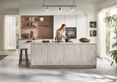 Helle moderne Wohnküche mit großer Kücheninsel und offener Regalwand im Hintergrund.