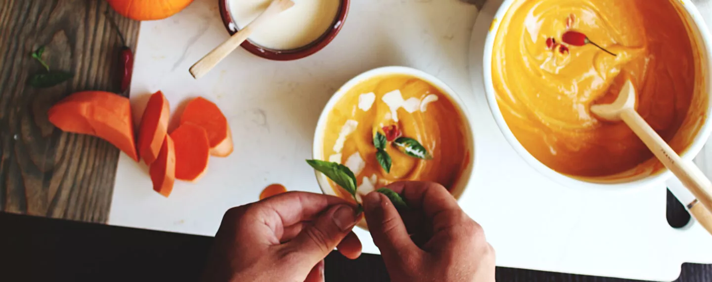 Frisch zubereitete Kürbissuppe mit Kürbisstücken und herbstlichen Zutaten – saisonale Rezeptidee für genussvolles Kochen in einer gut geplanten Küche.